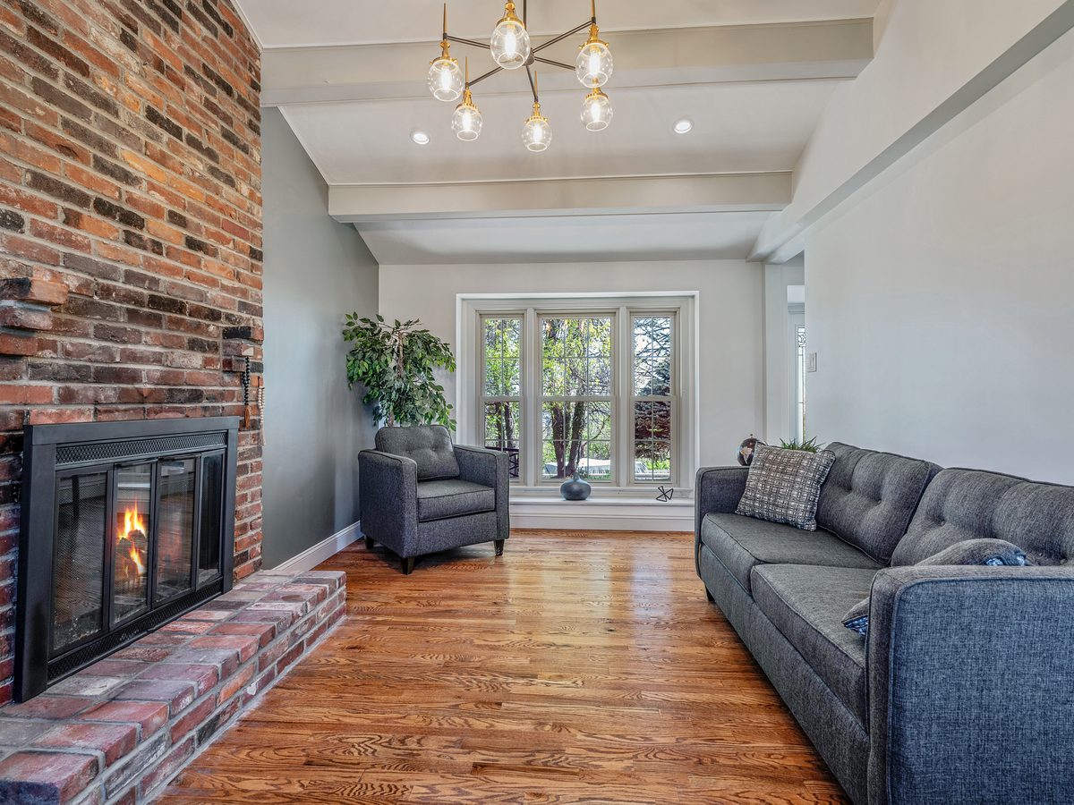 Finished living room with brick fireplace and hardwood floors