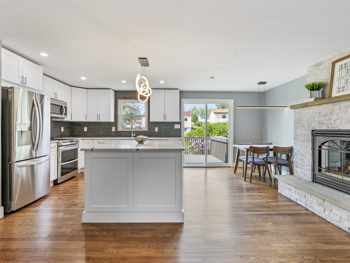 Finished open kitchen with white island and fireplace